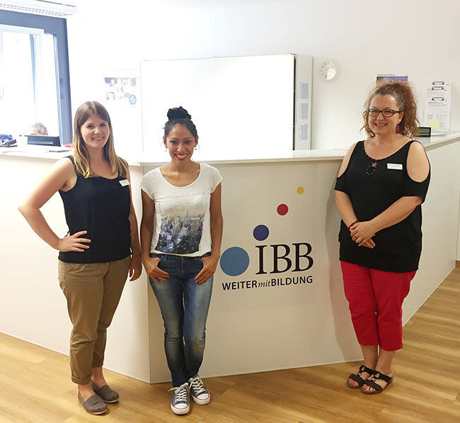 drei Frauen stehen vor einer weißen Wand mit dem IBB Logo darauf